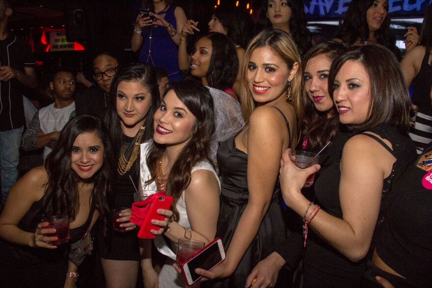 A group of women holding drinks pose for a picture.