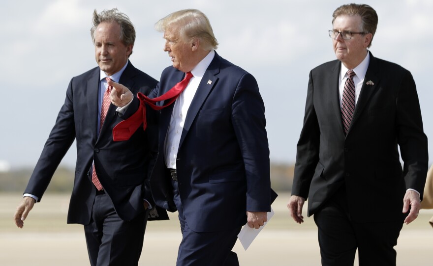 President Donald Trump walks with Texas Lt. Gov. Dan Patrick, right, and Texas Attorney General Ken Paxton at Austin-Bergstrom International Airport.