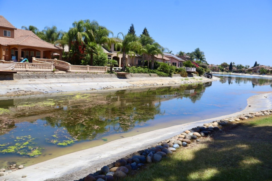 One of the lakes in Greenhills Estates sits at a significantly reduced water level on July 17, 2026, with algae spreading across the surface.