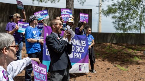 Daniel Tucker, a leader with the Missouri Workers Center, teaches chants customized to an initiative petition to raise the minumum wage and mandate paid sick leave outside of the Secretary of State's office building in Jefferson City Wednesday.