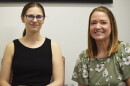 Two women smile for a photo during an interview held in a public radio station studio.  