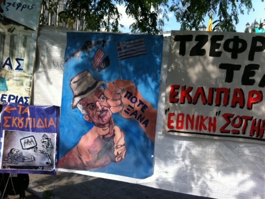<p>A poster depicts Greek Prime Minister George Papandreou as an American puppet. The words on the hand hitting Papandreou's face are "never again".</p>