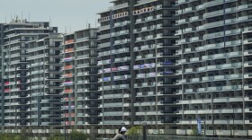 A man rides a bike near the village for the Summer Olympics in Tokyo. On Saturday, officials announced the first case of COVID-19 found at the center housing thousands of athletes.