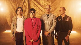 Group of four men stands together with glowing light behind them 