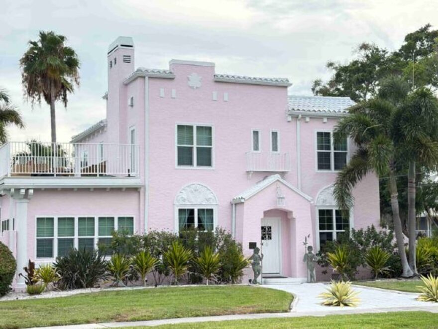 Picture of a pink two story house with trees around it 