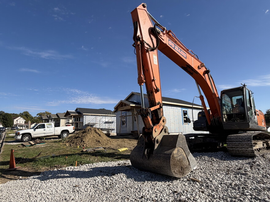a backhoe sits in front of two houses under construction