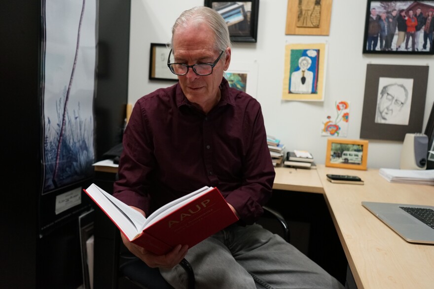 Photo of a man reading a large book.