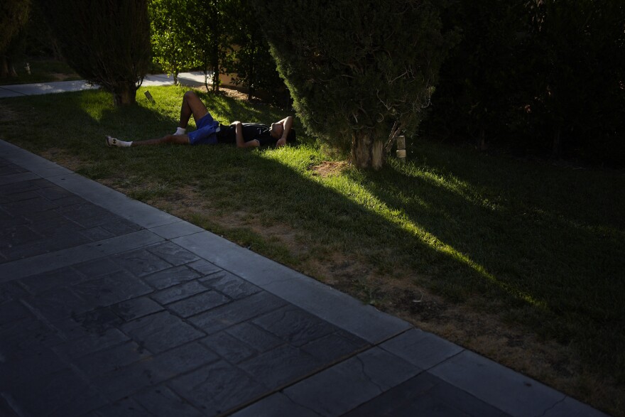 A person rests in partial shade along the Las Vegas Strip, Sunday, July 7, 2024, in Las Vegas. The city set an all time record high of 120 F (48.8 C) Sunday as a heat wave spread across the Western U.S. sending many residents in search of a cool haven from the dangerously high temperatures. (AP Photo/John Locher)