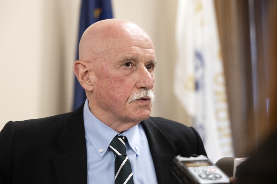  A man standing in front of flags speaks to reporters.