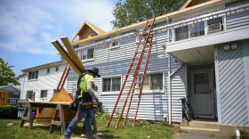 FILE, 2022: A construction worker carries lumber for the roof of a building being renovated in the Colonial Village public housing complex in Norwalk, adjacent to the Oak Grove Apartments and Learning Center site. The 7.6-acre development will include a 5,000 square-foot childcare center.