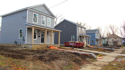 Row of three two story houses under construction.