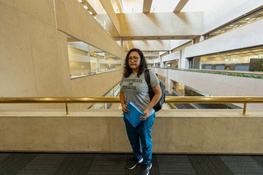 Janie Cisneros stands in Dallas City Hall while going back and forth between the city secretary and City attorney's office. Her blue folder holds all the documents needed to file for amortization.