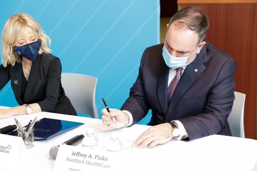 Jeffrey Flaks, president and CEO of Hartford HealthCare and Quinnipiac President Judy D. Olian sign a partnership to revamp Connecticut's hospital workforce with job training.