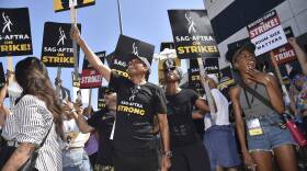 Picketers carry signs on the picket line outside Universal Studios. (Richard Shotwell/Invision/AP)
