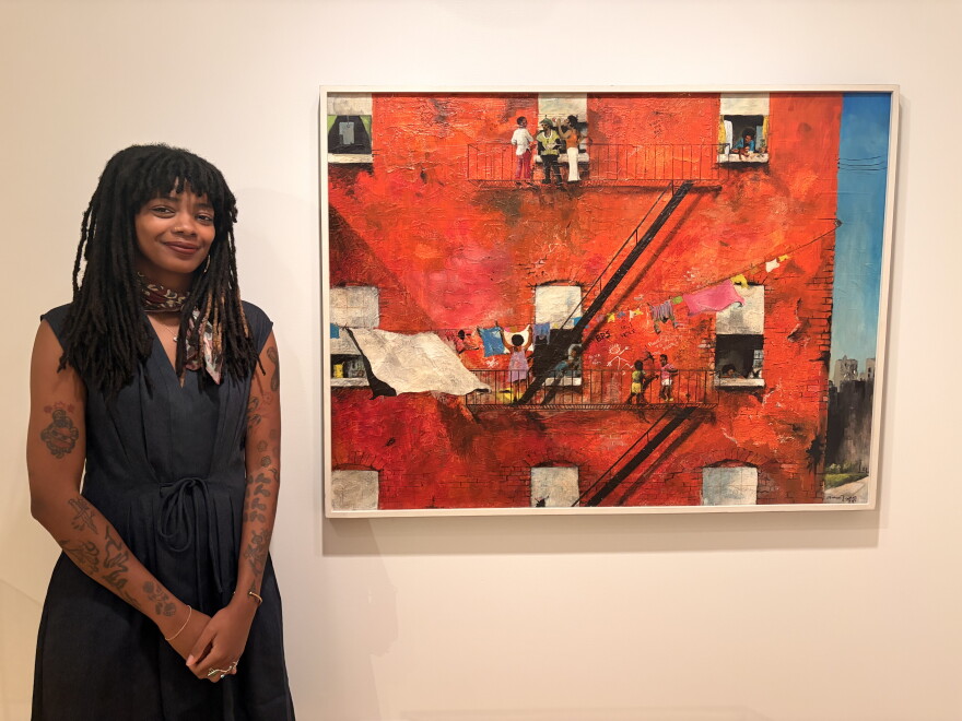 "Building Bronzeville" exhibition co-curator, Phoenix Brown, poses with a painting by Michael James Ward.