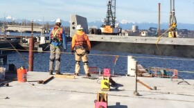 Workers prepare to snap in a new section of roadway on the east side of the SR 520 bridge.
