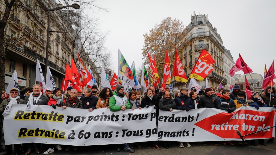 People hold a banner reading "Pension by points: we all lose. Retirement at 60: we all win" during a demonstration against a plan to overhaul national pensions in Paris.