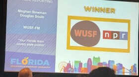 A large screen projects WUSF's logo with the text winner for political reporting Meghan Bowman and Douglas Soule WUSF-FM "Your Florida team covers state politics" 