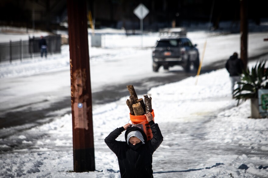 A pedestrian carries a bucket filled with firewood in South Austin during February's winter storm and blackouts.