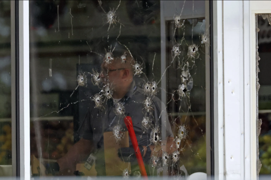 Damage can be seen to a front window as investigators work the scene of a shooting at the Mad Butcher grocery store in Fordyce, Arkansas on Friday, June 21, 2024.