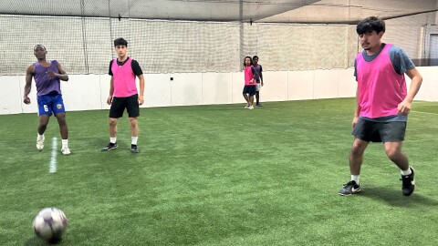 Players are playing five on five soccer on a turf soccer field 