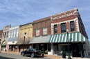 The view of a few shops in downtown Mexico, Missouri. The buildings appear older with unique facades of different colored brick. 