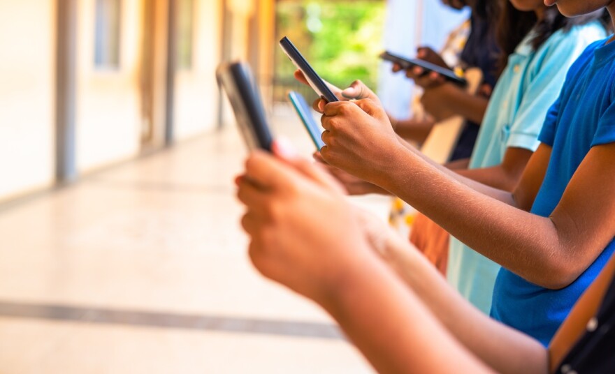 Close up shot of children's hands busy using smartphones in a school corridor