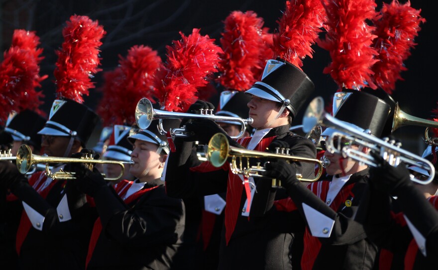 Fans and marching band members greet ISU football players and coaches