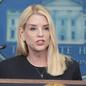 Attorney General Pam Bondi, a white woman with long blond hair in a black dress with a gold cross pendant 