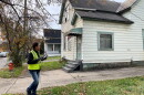 A man in a bright yellow safety vest inspects the exterior of a house in Cleveland. 