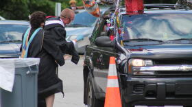 One of Manuel High School's teachers runs up excitedly to a vehicle during the school's drive-thru graduation.