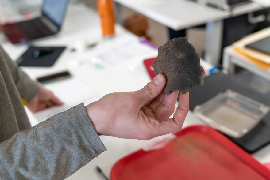 Matthew Hanks holds a pottery shard in the Army Corps of Engineers St. Louis office on Aug. 2, 2022. Hanks is part of the Corps Veterans Curation Program, which emplolys veterans to help maintain artifacts like this, which are unearthed in various Corps projects.