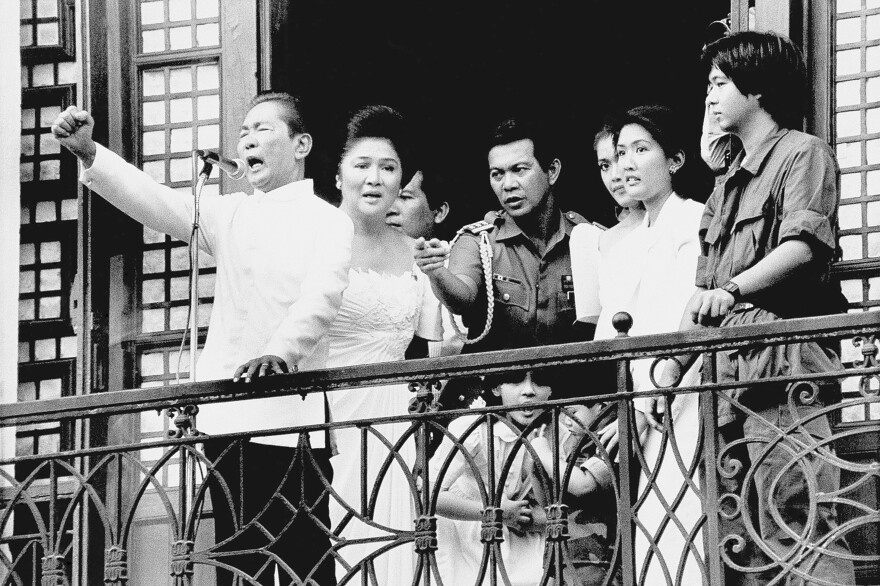 FILE - Ferdinand Marcos Sr., with his wife, Imelda, at his side and Ferdinand Marcos Jr., far right, gestures strongly from the balcony of Malacanang Palace on Feb. 25, 1986, in Manila, just after taking the oath of office as president of the Philippines.