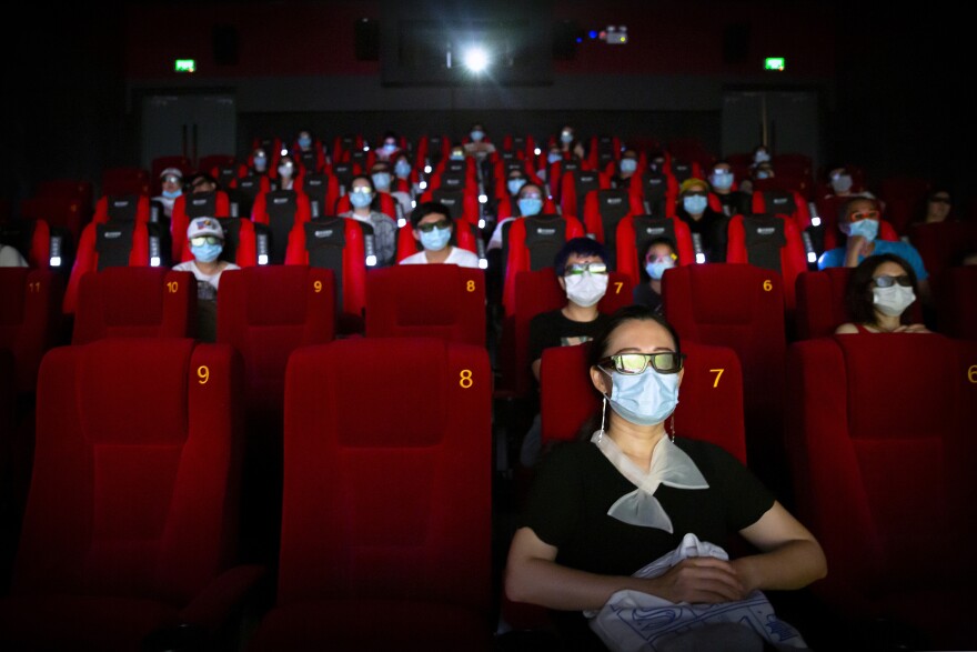 People wearing face masks to protect against the coronavirus sit spaced apart as they watch the film "Dolittle" at a movie theater in Beijing, Friday, July 24, 2020.