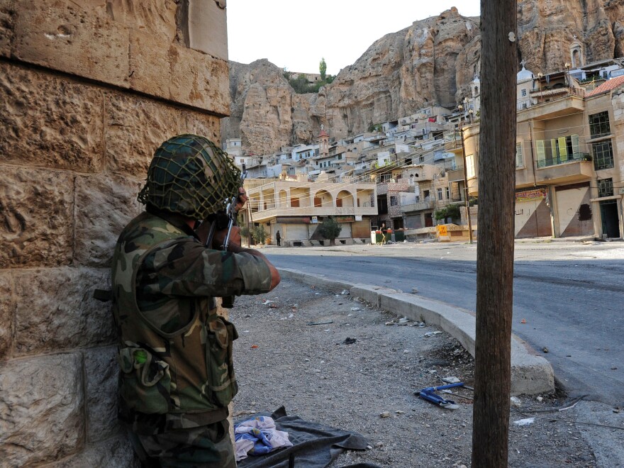 A Syrian government soldier aims his weapon during clashes with Free Syrian Army fighters in Maaloula, north of Damascus, in this photo released by the Syrian official news agency SANA in September.