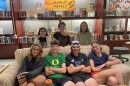 Seven students pose for a picture in front of books in a high school library.