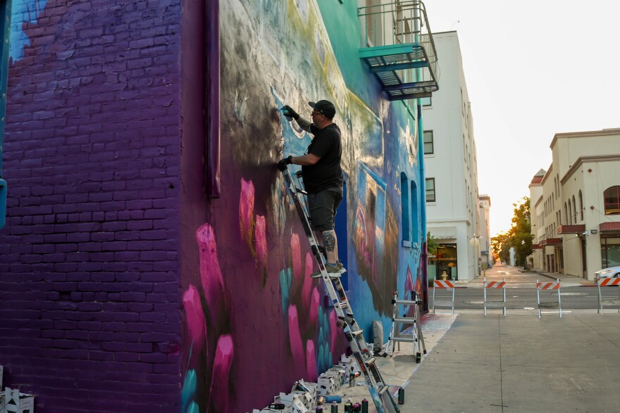 Joel Martin works on detailing his mural with a spray can.