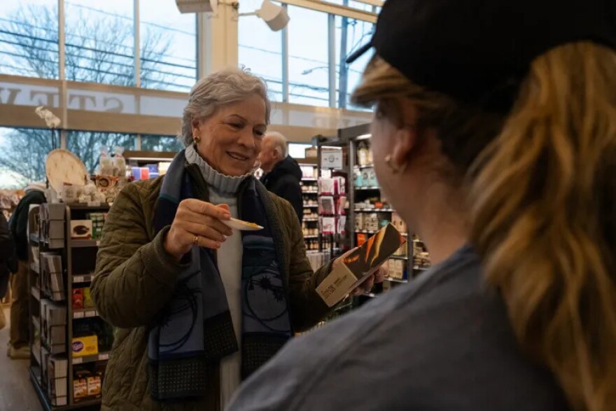 Suzie Binch, a customer at Walter Stewart’s Market, tries a sample from Fire Ox Foods during a product demo.