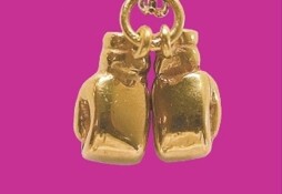 Charms depicting a pair of gold boxing gloves. The background is bright pink.