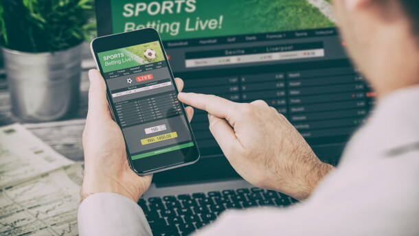 This stock image shows a man using his cellphone to access a sports betting site.