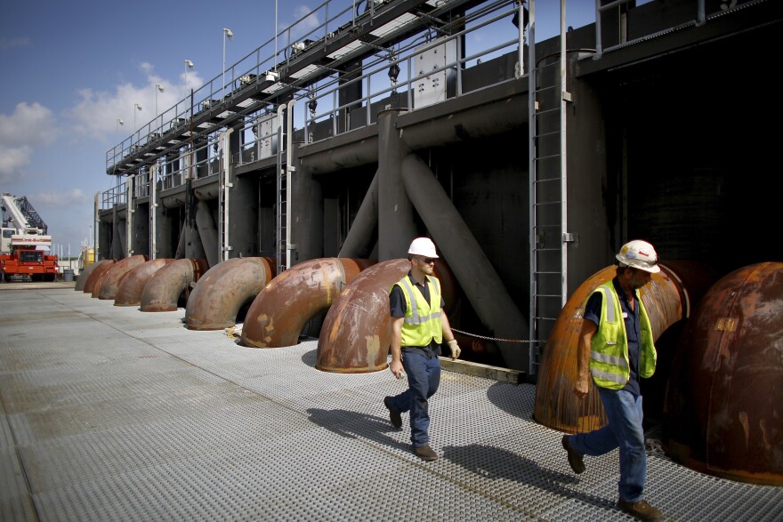 Maintenance crews walk across the flood gate and pumping station at the 17th Street Canal in New Orleans. The existing pump station will be replaced with a new flood protection barrier and pump house that's still under construction.