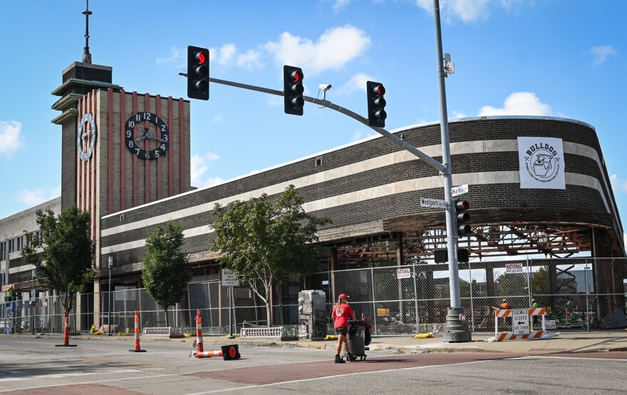 A woman pushes a a cart across the street at the intersection of Main Street and Westport Road near the remodeling of the former Katz Drug Co. building.