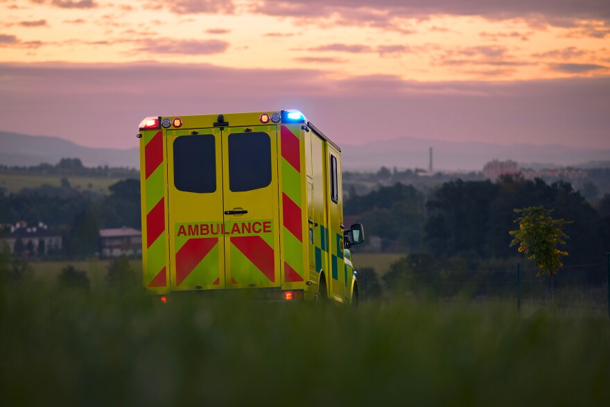 Yellow ambulance car of emergency medical service on country road. Themes rescue, urgency and health care.