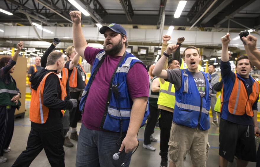 Amazon employee and ship dock manager Zach Mudd, center, leads a group chant as employees return from their lunch breaks at an Amazon fulfillment center on Friday, November 3, 2017, in Kent. 