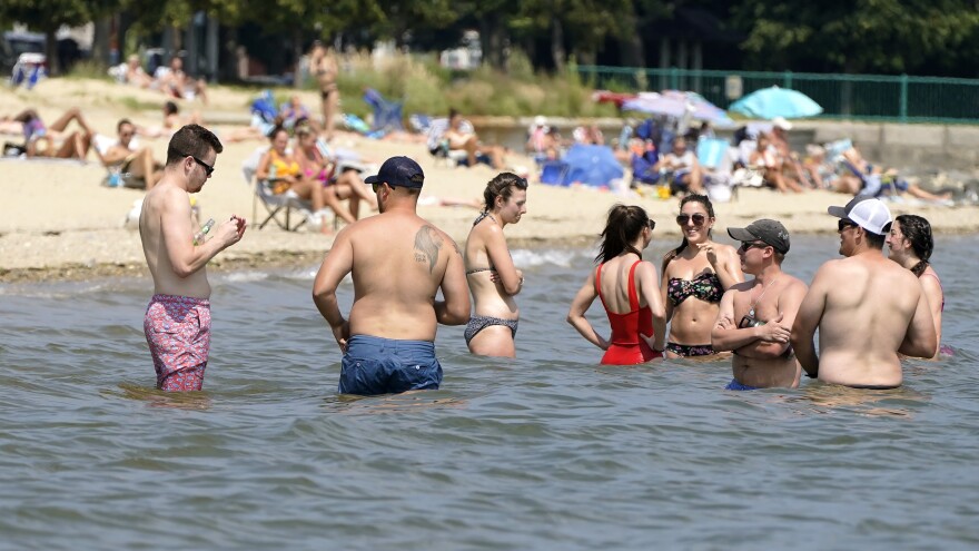 Beachgoers stand in the water of Dorchester Bay in Boston to cool off on Wednesday.