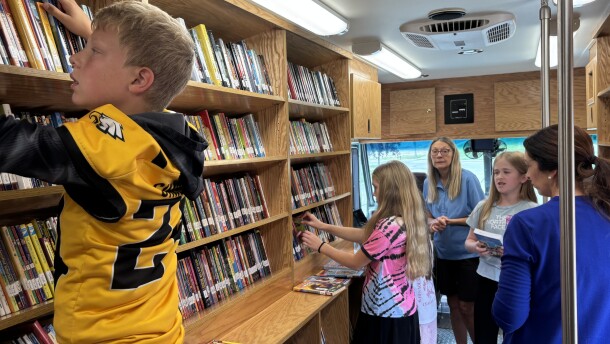 Students at the Lawton-Bronson School District in Bronson, Iowa, look over options in the Woodbury County Library bookmobile, as library director Donna Chapman look on on September 12, 2025. (Bret Hayworth, Siouxland Public Media News)