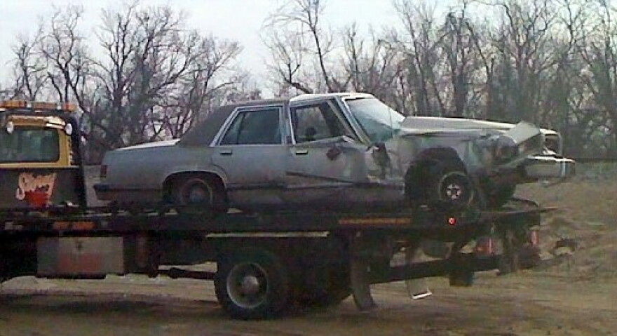 The damaged car is loaded onto a wrecker after the driver is taken to the hospital.