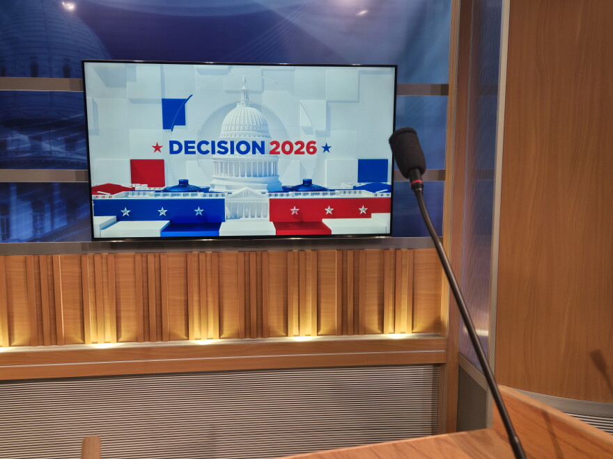 Decision 2026 graphic behind a podium microphone