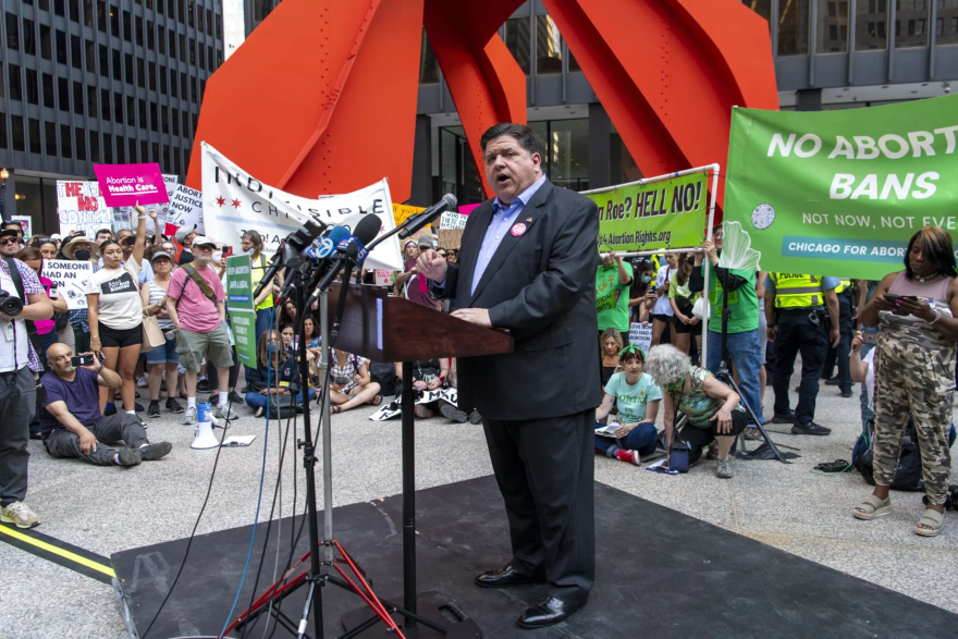 Gov. J.B. Pritzker is speaking into a podium, addressing an abortion rights rally at Federal Plaza held last year.