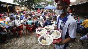 In this Feb. 23, 2018 photo, a volunteer at the "Divina Providencia" migrant shelter distributes lunch to Venezuelan migrants, in Cucuta, Colombia. The food is cooked in several large vats and the diocese says it offers an average of 1000 meals a day.